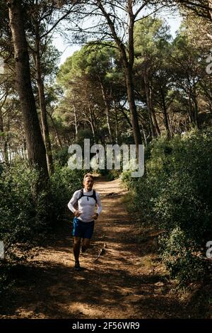 Uomo che corre su strada sterrata in foresta Foto Stock