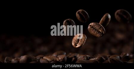 Primo piano, chicchi di caffè freschi che cadono sul terreno Foto Stock