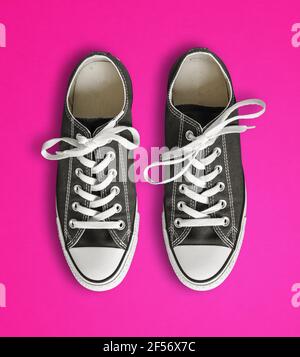 Sneaker generiche nere isolate su sfondo rosa Foto Stock