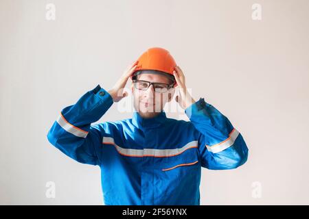 un giovane lavoratore maschio che tiene un casco, attrezzature di sicurezza industriale Foto Stock