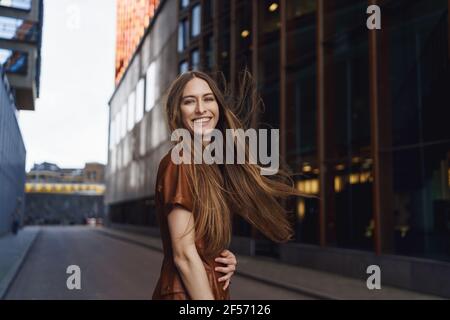 Ritratto esterno in vita di carismatica splendida donna che si diverte, si sente felice, ridendo come tornare indietro a sorridere macchina fotografica, camminando lungo la città vuota Foto Stock