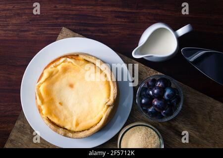 La cheesecake della nonna oltre alle uve e allo zucchero di canna su legno scuro scheda Foto Stock