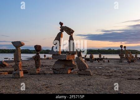 Rocce trasformate in arte, bilanciate su una spiaggia sul fiume Ottawa all'alba Foto Stock