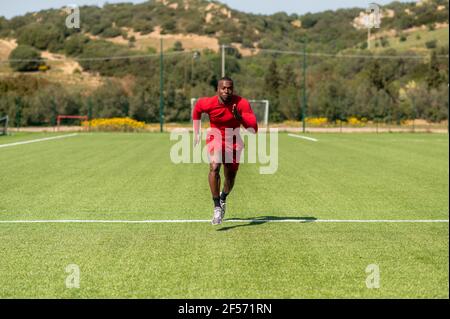 Vista frontale corridore afro-atletico che corre in un campo di calcio. Foto Stock