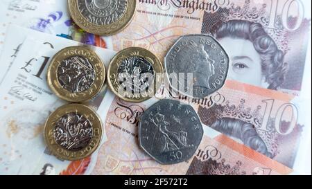 La valuta della sterlina inglese con le banconote in valuta polimerica e le monete in sterline Foto Stock