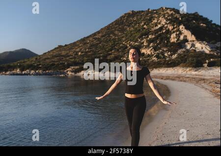 Giovane donna che cammina lungo il mare sulla spiaggia respirando aria fresca e pura. Foto Stock
