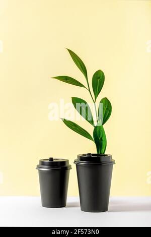 Due tazze da caffè riciclabili con foglia verde fresca Foto Stock