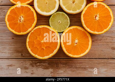 Arance, lime e limoni scivoli su tavola di legno vista da sopra.Beautiful Sfondo con frutta fresca metà cut.Healthy mangiare vitamina C.Summer tropic Foto Stock