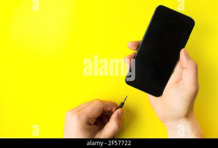 Primo piano di un caricabatterie via cavo in un telefono cellulare. Mano COSE UP mans inserimento di un caricabatterie in uno smartphone Foto Stock