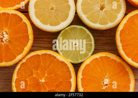 Arance, lime e limoni scivoli su tavola di legno vista da sopra.Beautiful Sfondo con frutta fresca metà cut.Healthy mangiare vitamina C.Summer tropic Foto Stock