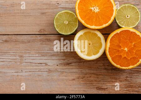 Arance, lime e limoni scivoli su tavola di legno vista da sopra.Beautiful Sfondo con frutta fresca metà cut.Healthy mangiare vitamina C.Summer tropic Foto Stock