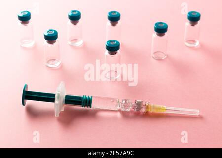 Siringa con diversi flaconcini medici per l'iniezione su sfondo rosa. Foto Stock