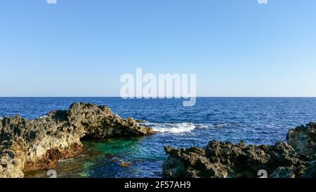 Splendido paesaggio acquatico dalla costa rocciosa della spiaggia di Ognina, Sicilia Foto Stock