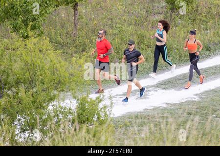 Un gruppo di quattro giovani corre sulla strada di campagna Foto Stock