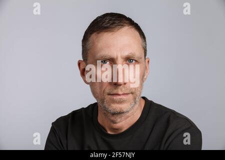 Barba uomo che indossa una t-shirt su sfondo grigio chiaro. Scatto in studio. Foto Stock