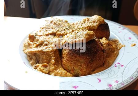 Fuoco selettivo di una cucina indiana calda e affumicata deliziosa Curry Malai Kofta al forno - un piatto di specialità Mughlai fatto di noci di anacardi servite su un piatto Foto Stock