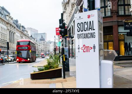 REGENT STREET, LONDRA, INGHILTERRA - 17 febbraio 2021: Testo di allontanamento sociale su un dispenser di disinfettante per mani pubblico su Regent Street, durante l'ultimo lo Foto Stock