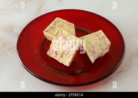 Fragola rabarbaro bianco cioccolato pezzi da bar pezzi su vetro rosso piatto da dessert Foto Stock