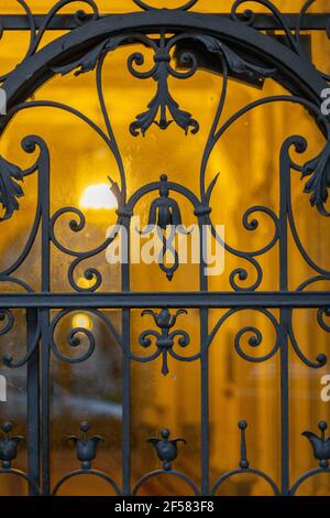 Grigliata in ferro battuto ornata su una vecchia porta in vetro Foto Stock