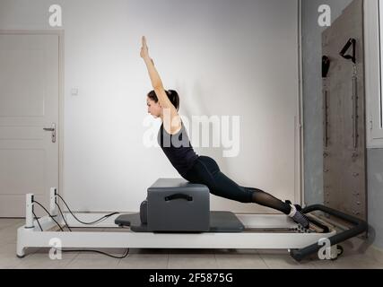 Una donna che fa esercizi pilates su un letto riformato. Foto Stock