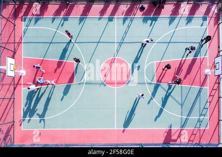 Gli uomini giocano a streetball in un campo all'aperto dall'alto verso il basso, vista aerea Foto Stock