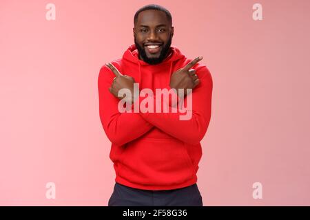 Felice bel ragazzo bearded che punta i lati diversi croce dita sinistra giusto sorridente felicemente chiedendo parere alla ragazza consiglio che scelta fanno Foto Stock