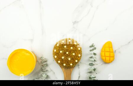 Un mango giallo fatto a mano sapone, un ramo di eucalipto, una spazzola per il massaggio, olio giacciono su un tavolo bianco. Concetto positivo per il corpo Foto Stock