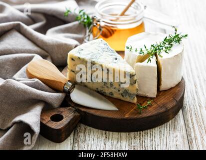 Vari tipi di formaggio, formaggio blu, preda, camambert e miele su un tavolo di legno Foto Stock