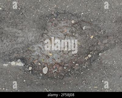 Primo piano su di un Pothole su una tranquilla strada di campagna Tarmac in Devon rurale, Inghilterra, Regno Unito Foto Stock