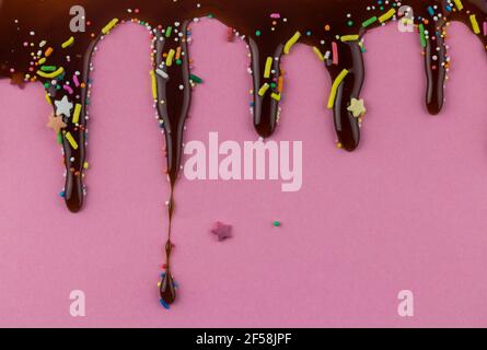 Gocce di cioccolato su sfondo rosa con puntini, spruzzi e stelle di divertimento - copy spazio per la carta di invito compleanno Foto Stock