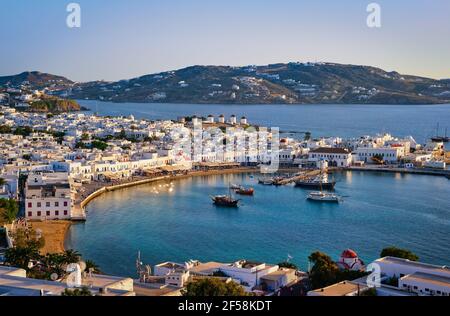 Splendida vista del tramonto sulla città di Mykonos, la Grecia e il porto. Ora d'oro, porto, navi da crociera, case bianche. Vacanze, stile di vita mediterraneo Foto Stock