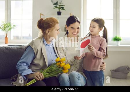 Donna felice che ottiene i regali dalla piccola figlia e dalla madre anziana Il giorno della Madre Foto Stock