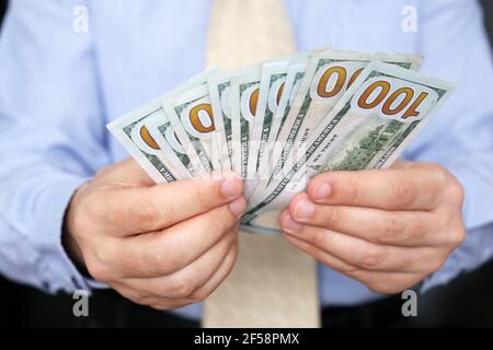 DOLLARI USA in mano maschile da vicino, uomo in abiti da lavoro con soldi. Concetto di tangente, stipendio, successo, assistenza finanziaria o prestito Foto Stock