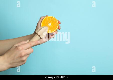 Le mani femminili tengono l'arancione e la centrifuga su sfondo blu Foto Stock