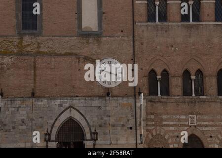 L'Orologio d'epoca che si aggancia su un vecchio muro di mattoni Siena Toscana Italia Foto Stock