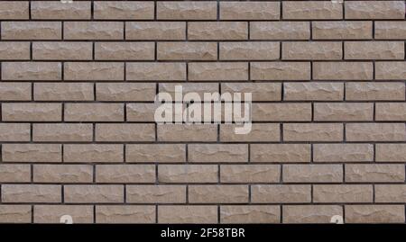 Brick beige con superficie zigrinata e scheggiata. Affilatura pulita per motivi di sfondo. Piastrelle rettangolari mosaico parete ad alta risoluzione. Vecchio o artificiale Foto Stock