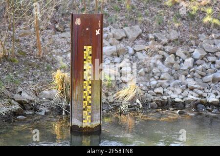 Indicatore di livello di allagamento metrico giallo nel fiume con acque basse livello Foto Stock