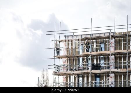 Scaffolder PPE costruzione telaio alti pali ponteggi in alto moderno nuovo cantiere di costruzione. Attrezzature e attrezzi pericolosi per la sicurezza del lavoro Foto Stock