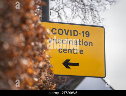 Covid-19 Coronavirus pandemia vaccinazione centro di test informazioni giallo segnale stradale per i cittadini che vanno vaccinati con la freccia Foto Stock