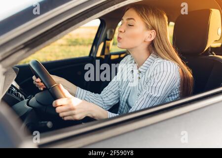 Giovane donna felice compra un'automobile, signora in un salone dell'automobile, donna esultante elegante Foto Stock
