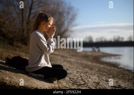 Pratica della meditazione e dell'interazione con la natura. Ragazza vicino al fiume Foto Stock