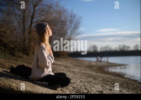 Pratica della meditazione e dell'interazione con la natura. Ragazza vicino al fiume Foto Stock