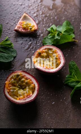 frutta tropicale frutto della passione su sfondo scuro con gocce d'acqua e foglie di menta copyspace Foto Stock