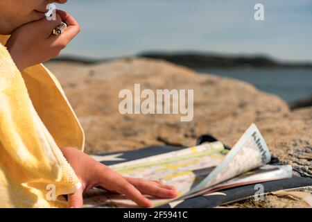 Donna che si rilassa sulla spiaggia risolvendo Crosswords durante la giornata estiva di vacanza. Foto Stock