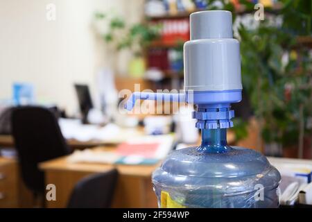 Grande bottiglia di plastica con dispenser blu in ufficio, spazio per fotocopie Foto Stock