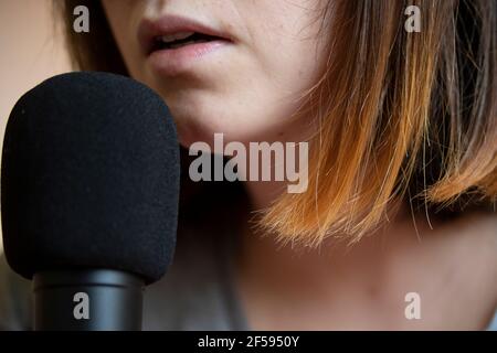 Giovane caucasica bianca che fa un podcast di fronte un microfono Foto Stock