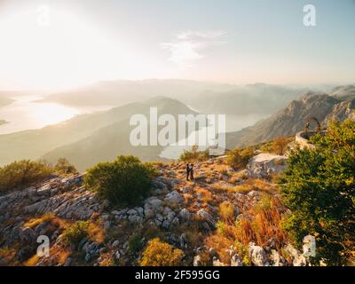 La sposa e lo sposo abbracciano il monte Lovcen alle spalle Si apre una vista sulla baia di Cattaro Foto Stock