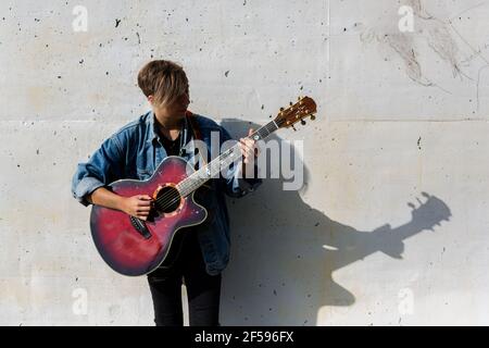 Woodbridge, Suffolk, UK Settembre 13 2020: Una 20 qualcosa di femminile rilassante e suonare una chitarra acustica fuori per i passanti da ascoltare anche Foto Stock