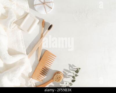 Vari articoli eco-compatibili: Spazzolini da denti, spazzola per capelli, salviette di cotone riutilizzabili, salvietta bianca e spazzola per il viso su sfondo bianco. Vista dall'alto. Spazio di copia Foto Stock