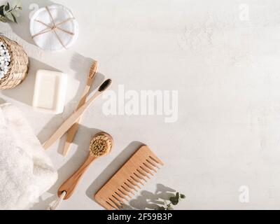 Vari articoli eco-compatibili: Spazzolini da denti, spazzola per capelli, salviette di cotone riutilizzabili, salvietta bianca e spazzola per il viso su sfondo bianco. Vista dall'alto. Spazio di copia Foto Stock